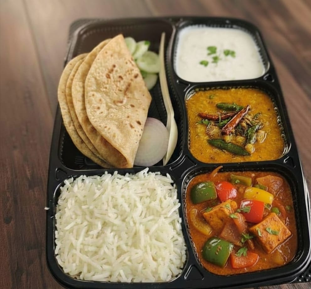 Fresh homestyle Indian thali with roti, rice, dal, paneer and raita